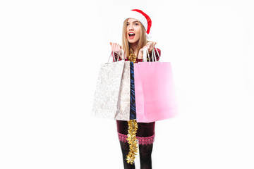 woman in shock, wearing a santa hat, with christmas bags in her hand.