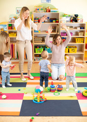 family, childhood, activity and creativity concept - happy mothers and their little kids having a fun in playroom