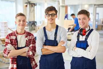 Smiling confident young carpentry students in blue uniform standing in line and looming at camera...