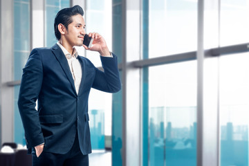 Handsome asian businessman standing while talking on the cellphone