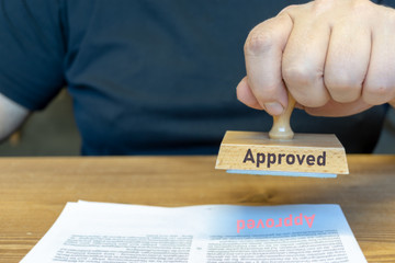 Close-up Of Person Hands Using Stamper On Document With The Text Approved