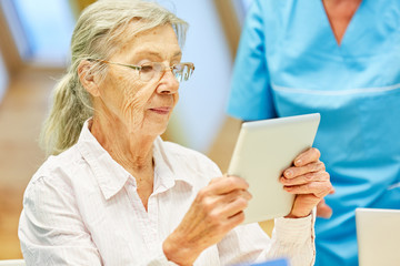 Alte Frau lernt konzentriert mit dem Tablet