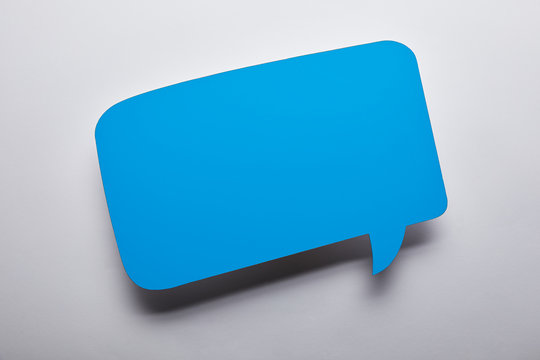 top view of empty blue speech bubble on grey background