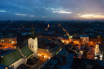 Panoramic night cityscape view on roofs,lights center and domes of Lviv city, Ukraine with a sun flare