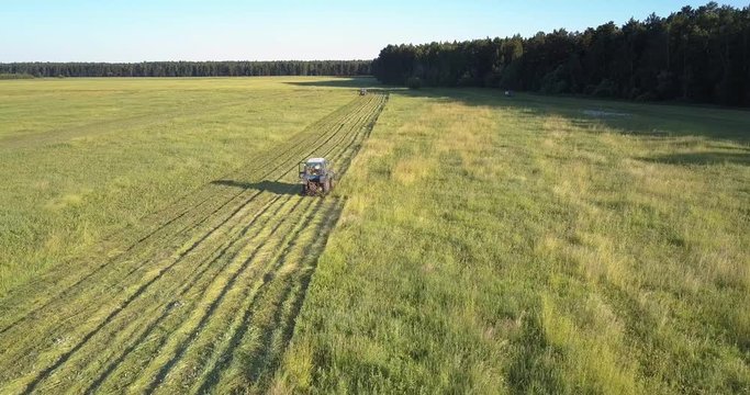 machine with rotary cutters mows grass on ground under sky