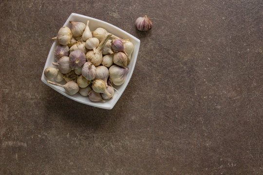 Garlic in a white Cup on a brown stone kitchen stoleshnicy. seasoning