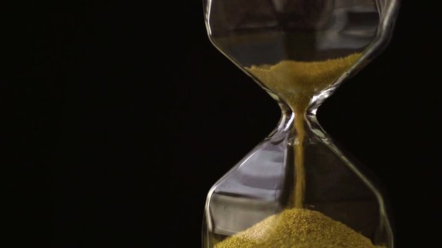 4k slow motion ,The sand flow in the hourglass with black background
