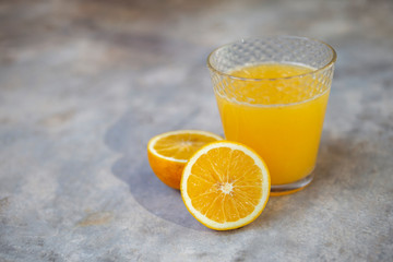 Fresh orange juice with fresh slice of orange on cement floor background, healthy drink