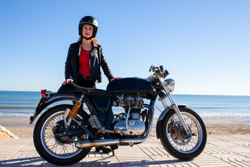 Fototapeta na wymiar Mujer con moto y casco junto a la playa
