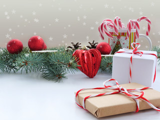 Christmas background with fir branches, decorations, gifts and candy cane over white table.