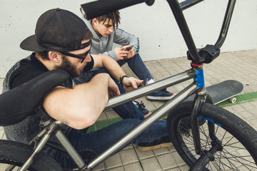 Young guys watching the mobile on the street. Modern lifestyle of young people