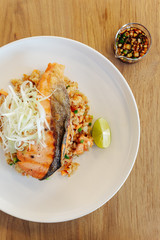 Garlic fried rice with grilled salmon on wooden table background.