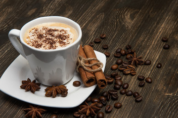 Cup of coffee on dark background. With cinnamon sticks, coffee beans and star anise