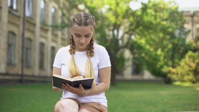 Teenager presenting flowers to girlfriend who reading book, refusal, ignoring