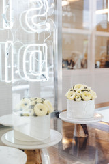 White cake with butter cream flowers decorated on stand in display.