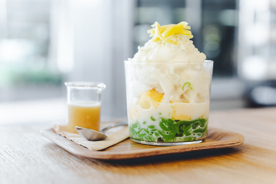 Lod Chong, Thai melon, puffed rice with coconut snow ice topping with sliced jackfruit. Served with caramel on wooden table with blur background.