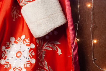 Close-up of red Santa Claus fur coat, Santa clothes and garland, new year background,
