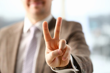 bright picture of handsome business man showing victory sign