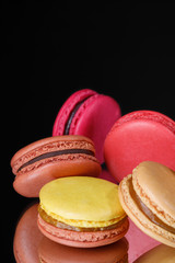 Colorful pastel macaroons on black background. Sweet macarons.