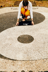 Young woman practicing yoga - meditation in the tropical garden with yin yang sign.