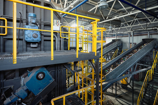 Refiner and chain-stepped conveyor equipment of modern waste recycling plant transports waste from receiving department to sorting, recycling and disposal