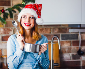 Beautiful young woman at kitchen with pan and spoon. Christmas time