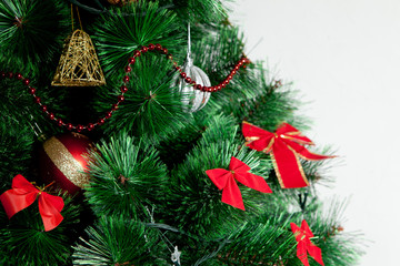 Close up of decorated christmas tree with colorful balls over white wall