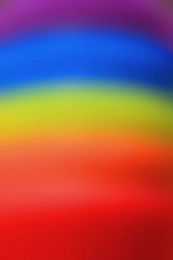 Vertical image of abstract blurred rainbow colored rubber rings stack 