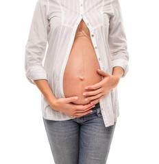 Pregnant woman in a white shirt and jeans on a white background.