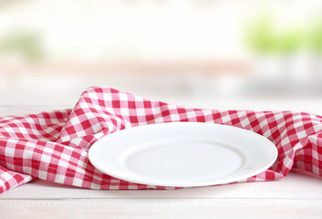 Empty plate checkered gingham cloth towel on table empty space.