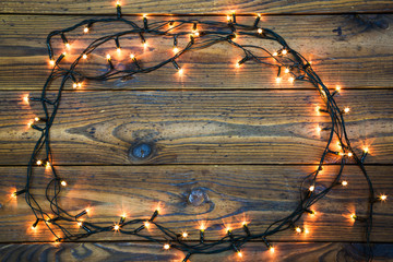 Fototapeta na wymiar Christmas lights on dark wooden table with copy space. Christmas lights frame