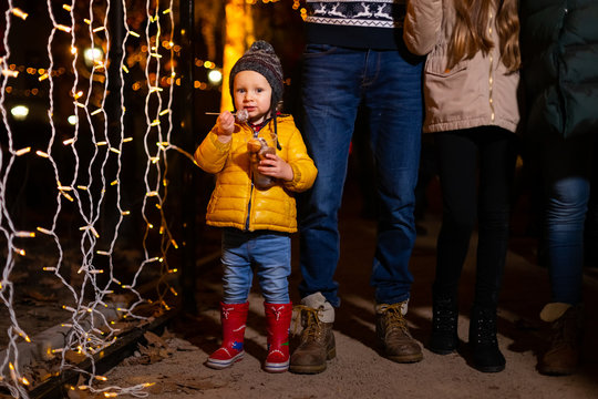 Young boy holding traditional food in frot of family at Christmas market.