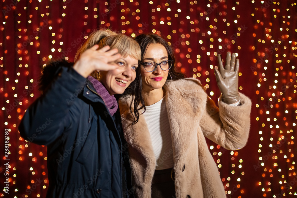 Wall mural two attractive women posing for photo at christmas market.