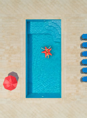 Aerial view of woman on star shapes inflatable mattress in swimming pool.