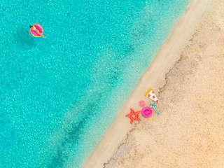 Aerial view of woman floating on inflatable mattress by sandy beach.