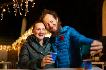 Couple taking selfie at traditional Christmas market, Zagreb, Croatia.