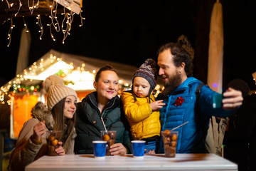 Father taking selfie with family at traditional Christmas market.