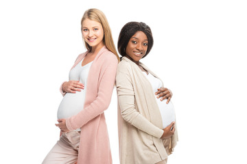 multicultural smiling pregnant women looking at camera isolated on white