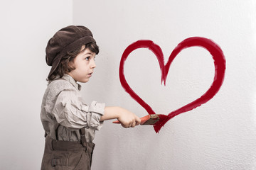 Kind malt ein Herz an die Wand
