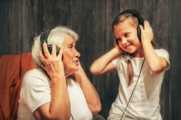 old woman and little girl in headphones listening to music grandmother and granddaughter