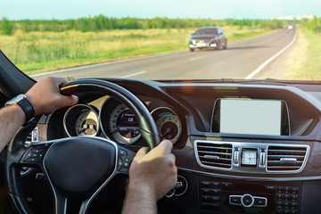 Fototapeta premium car driving, a man with a beard, sitting behind the wheel of a car and holding the wheel looks at the map