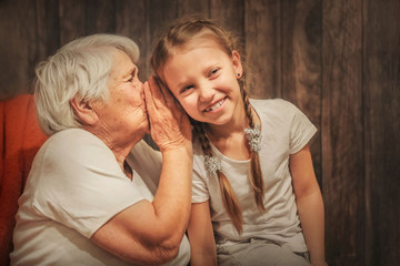 grandmother whispers in her ear to the granddaughter, time with loved ones