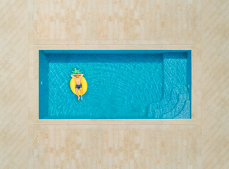 Aerial view of man on pineapple shaped inflatable mattress in swimming pool. - 238186938