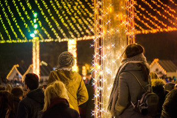 Christmas market and concert in city centre. People enjoying event, taking pictures and videos. Beautiful decorations and glowing lights.  