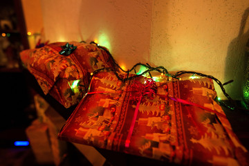Decorated Christmas gifts standing in shelf next to Christmas lights 