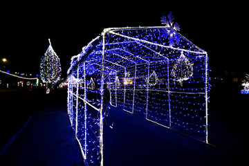 Glowing snowflakes and light stripes on dark, romantic night sky background. Beautiful Christmas market and decorations in city center. 
