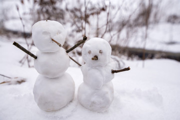 Two real tiny, little snowman in nature in snowy, cold day in mountains. Concept of beautiful...