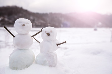 Two real tiny, little snowman in nature in snowy, cold day in mountains. Concept of beautiful...