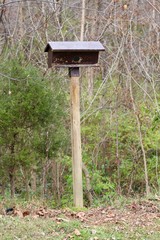 A wood birdhouse on a tall wooden post and a close view.