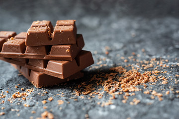 Selective focus Broken chocolate pieces and cocoa powder on  stone background